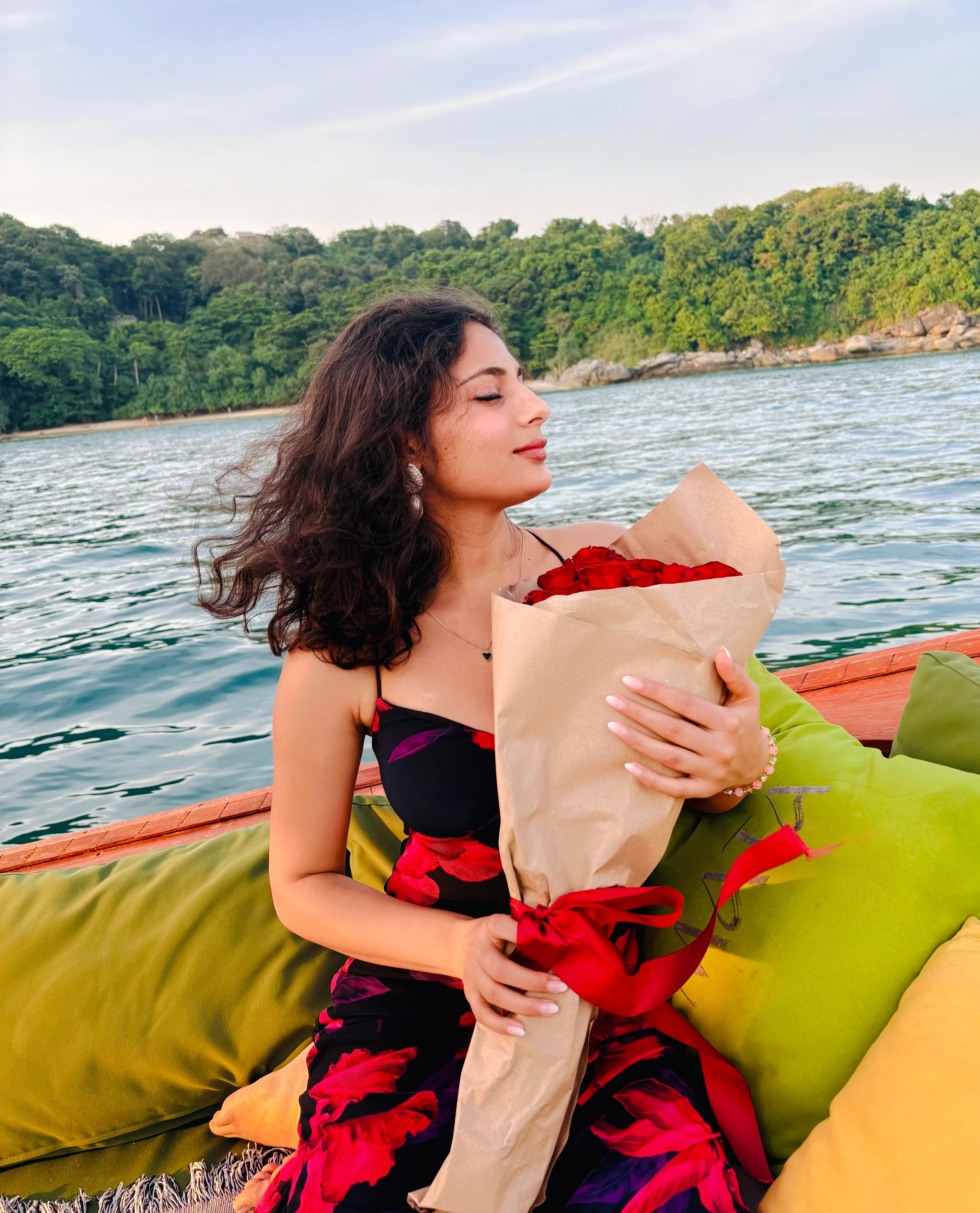 Khushboo holding red roses on a boat